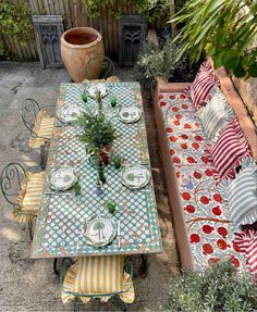 an outdoor table and chairs are set up for a meal in the back yard with potted plants