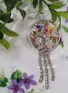 a close up of a plate with flowers on it and a brooche hanging from the side