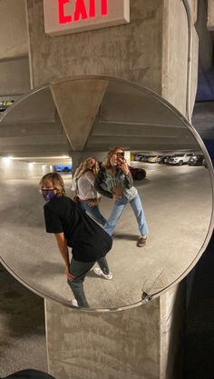 two women are standing in front of a mirror and one is talking on her cell phone