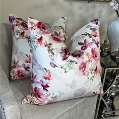 two pillows sitting on top of a couch next to a vase with flowers in it