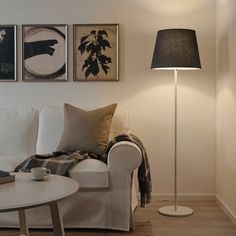 a white couch sitting next to a table with a lamp on it's side