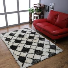 a living room with a red couch and black and white area rug on the floor