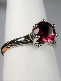 Simulated Red Ruby Ring Wedding #D22 This is a Victorian Era solitaire ring. This lovely sterling silver wedding solitaire has an approximately .5 carat simulated red ruby gemstone. This full cut flawless gemstone is 6mm (1/4") in diameter. The inside of the band is marked 925 for sterling silver. Notice the beautiful crown design of the silver filigree setting and the etched band. This is a lovely rendition of an Antique filigree ring. Classically fashioned, this ring is a vintage wedding style Classic Promise Jewelry With Lab-created Ruby, Classic Lab-created Ruby Jewelry For Promise, Classic Promise Ruby Solitaire Ring, Classic Solitaire Ruby Ring For Promise, Classic Solitaire Ruby Promise Ring, Classic Ruby Ring For Promise With Prong Setting, Promise Ruby Ring With Prong Setting, Classic Round Band Lab-created Ruby Jewelry, Formal Solitaire Ruby Ring With Round Stone