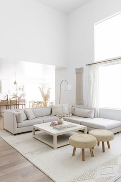 a living room filled with furniture and a large white rug on top of a hard wood floor