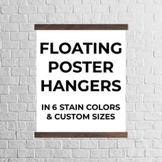 a white brick wall with the words floating poster hangers in 7 stain colors and custom sizes