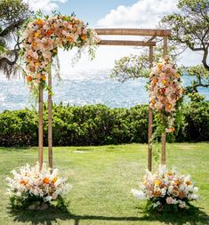 an outdoor ceremony setup with flowers and greenery on the grass near the ocean in hawaii