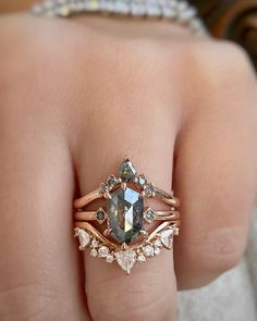 a woman's hand with two rings on it and an engagement ring in the middle