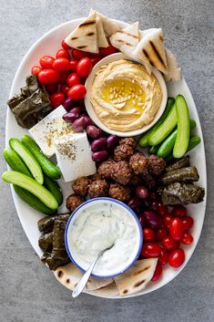 a platter filled with meat, vegetables and dip