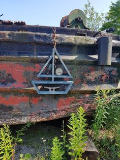 an old rusted out boat with a clock on it's face and some plants