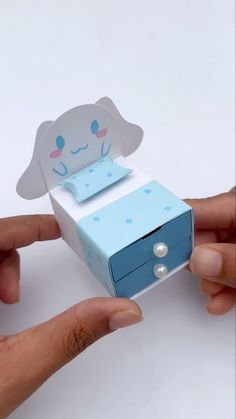 two hands are holding an origami box with a dog on it and another hand is opening the box