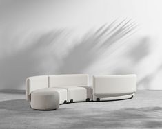 a white couch sitting on top of a cement floor next to a chair and ottoman