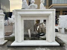 a white marble fireplace with statues in the back ground and buildings in the background behind it