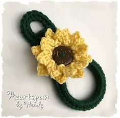 a crocheted yellow and green flower with a brown button on it's end