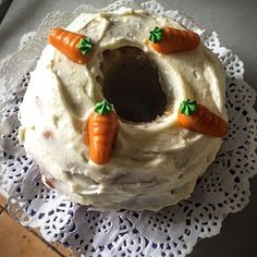 a cake with carrots on it sitting on a doily next to a knife