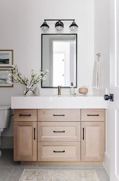 a bathroom with white walls and wooden cabinets