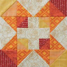 an orange and yellow patchwork quilt with roses on the top, along with other patterns