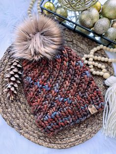 a knitted hat sitting on top of a rug next to ornaments and balls in a basket