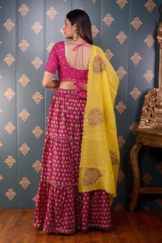 Rani pink tiered lehenga with floral block print motifs and gota patti trim on the hem. Comes with mirror embroidered blouse and mustard yellow floral print dupatta.
Component: 3
Pattern: Print and Embroidery
Type Of Work: Block Print and Mirror
Neckline: Round
Sleeve Type: Half
Fabric: Lehenga: Cotton Silk, Blouse: Banarasi Chanderi and Dupatta: Chanderi
Color: Pink
Other Details: 
Printed dupatta with scalloped border
Tie up with tassels on the side
Lace trim on the neckline and sleeve hems
Lo Block Print Lehenga, Tiered Lehenga, Print Motifs, Rani Pink, Floral Block Print, Scalloped Border, Mirror Round, Printed Dupatta, Pink Lehenga