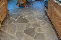 a kitchen with stone flooring and wooden cabinets