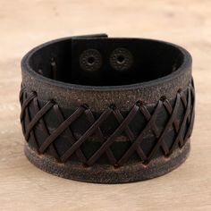 a brown leather bracelet with braiding on the inside and two holes in the middle