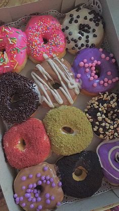 a box filled with lots of different flavored donuts on top of a table