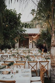 an outdoor dining area with tables and chairs set up for a formal dinner in the garden