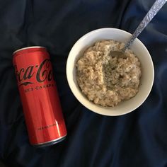 a bowl of oatmeal and a can of coca cola on a bed