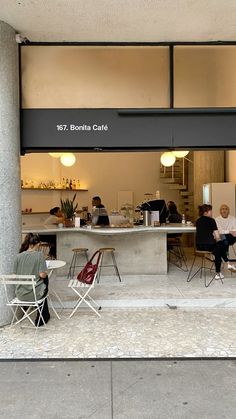 people are sitting at tables in front of a building with an open door that says bonita cafe