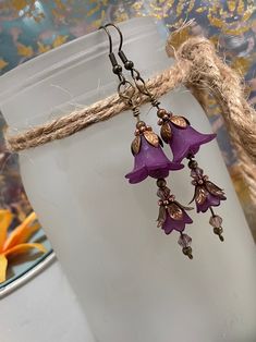 two purple flowers are hanging from some kind of earring that is attached to a rope