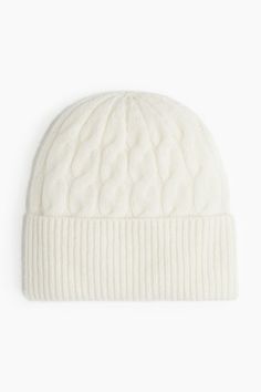 the cable knit beanie hat in white is shown from front view, and has a rib