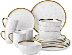 a white and gold dinner set with matching cups, saucers, and plates on a white background