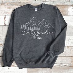 "Embrace the natural beauty and adventurous spirit of Colorado with our \"Colorado\" Sweatshirt. This cozy sweatshirt is more than clothing; it's a tribute to the breathtaking landscapes and outdoor adventures of the Centennial State. The sweatshirt features a captivating design that pays homage to Colorado's stunning mountains, forests, and outdoor wonders. 🎁 Perfect Souvenir: Whether you're a Colorado native, a visitor, or simply an admirer of this majestic state, this sweatshirt makes a perf Fall Hiking Crew Neck Sweatshirt, Fall Hiking Sweatshirt Crew Neck, Fall Crew Neck Sweatshirt For Adventure, Fall Crew Neck Sweatshirt For Hiking, Long Sleeve T-shirt For Fall Adventure, Winter Adventure Crew Neck Sweatshirt, Winter Crew Neck Sweatshirt For Adventure, Fall Adventure Letter Print Sweatshirt, Letter Print Sweatshirt For Fall Adventure