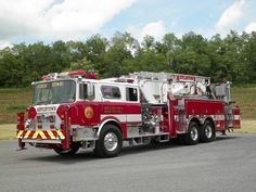 a red fire truck parked on the side of the road with trees in the background