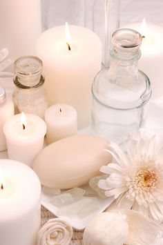 white candles and flowers on a table with glass containers filled with water, salt and pepper