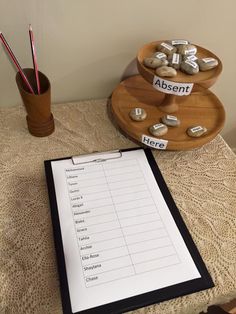 a table topped with a clipboard next to a cup full of rocks and pencils