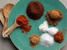 various spices are arranged on a plate with spoons