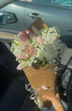 a person holding a bouquet of flowers in the back seat of a car on a sunny day