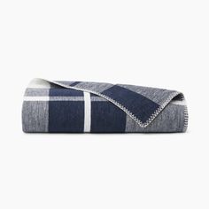 a blue and white plaid blanket folded on top of a bed with the cover pulled down