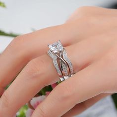 a woman's hand with a wedding ring on it and flowers in the background