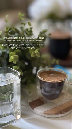 a cup of coffee sitting on top of a table next to a vase filled with flowers