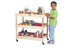 a young boy standing next to a wooden cart filled with art supplies