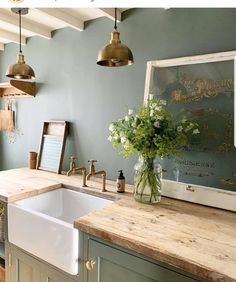 a kitchen with blue walls and wooden counter tops, an old fashioned faucet hangs over the sink