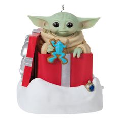 a star wars ornament with a baby yoda holding a gift box in it