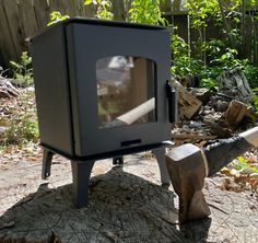 an old tv sitting on top of a tree stump in the woods with a hammer sticking out of it