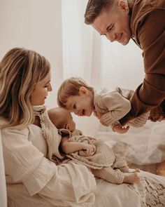 a man is holding a baby while two other people are looking at him and smiling