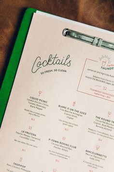 the menu for cocktails is displayed on a clipboard with a pen in it