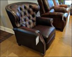 two brown leather recliners sitting next to each other in a room with hardwood floors