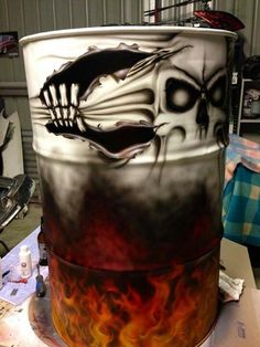 a large metal barrel with flames and skulls painted on it