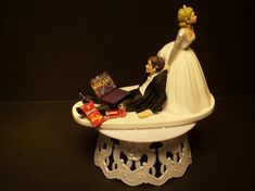 a wedding cake topper with a bride and groom sitting on a bathtub holding each other