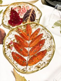 two plates with leaves on them sitting on a table